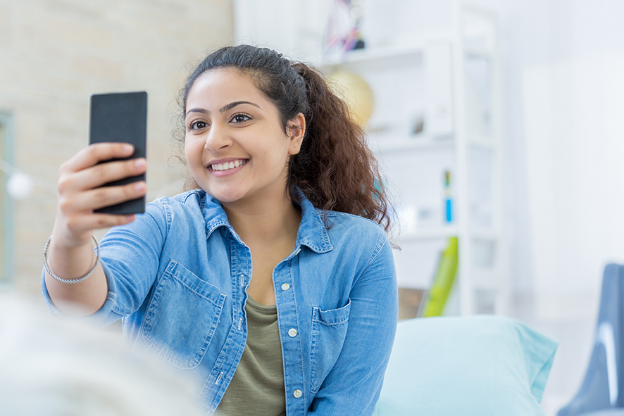 Teenager taking a photo of her invisalign journey to upload to the dental monitoring app
